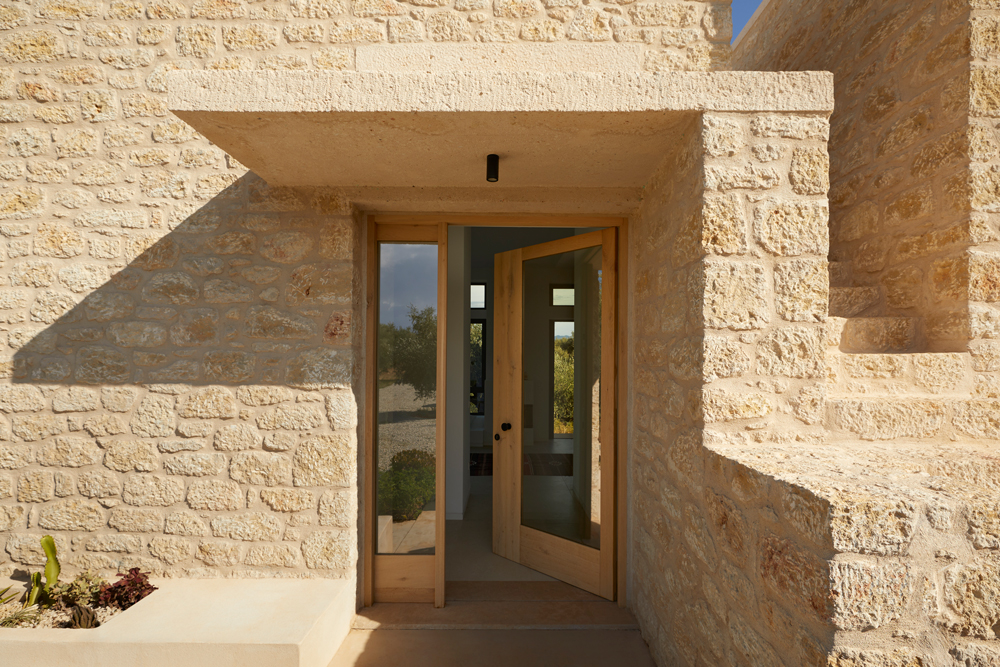 Stone façade catching sunlight above the Messinian coastline
