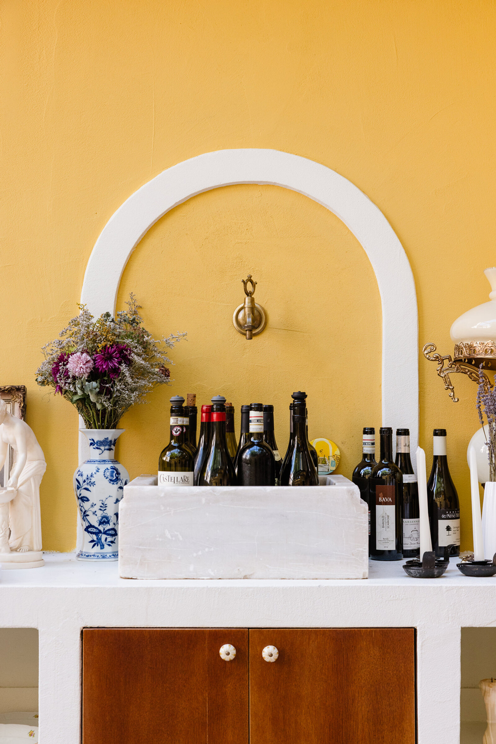 Old marble sink filled with empty wine bottles, adding a rustic focal point to the courtyard.