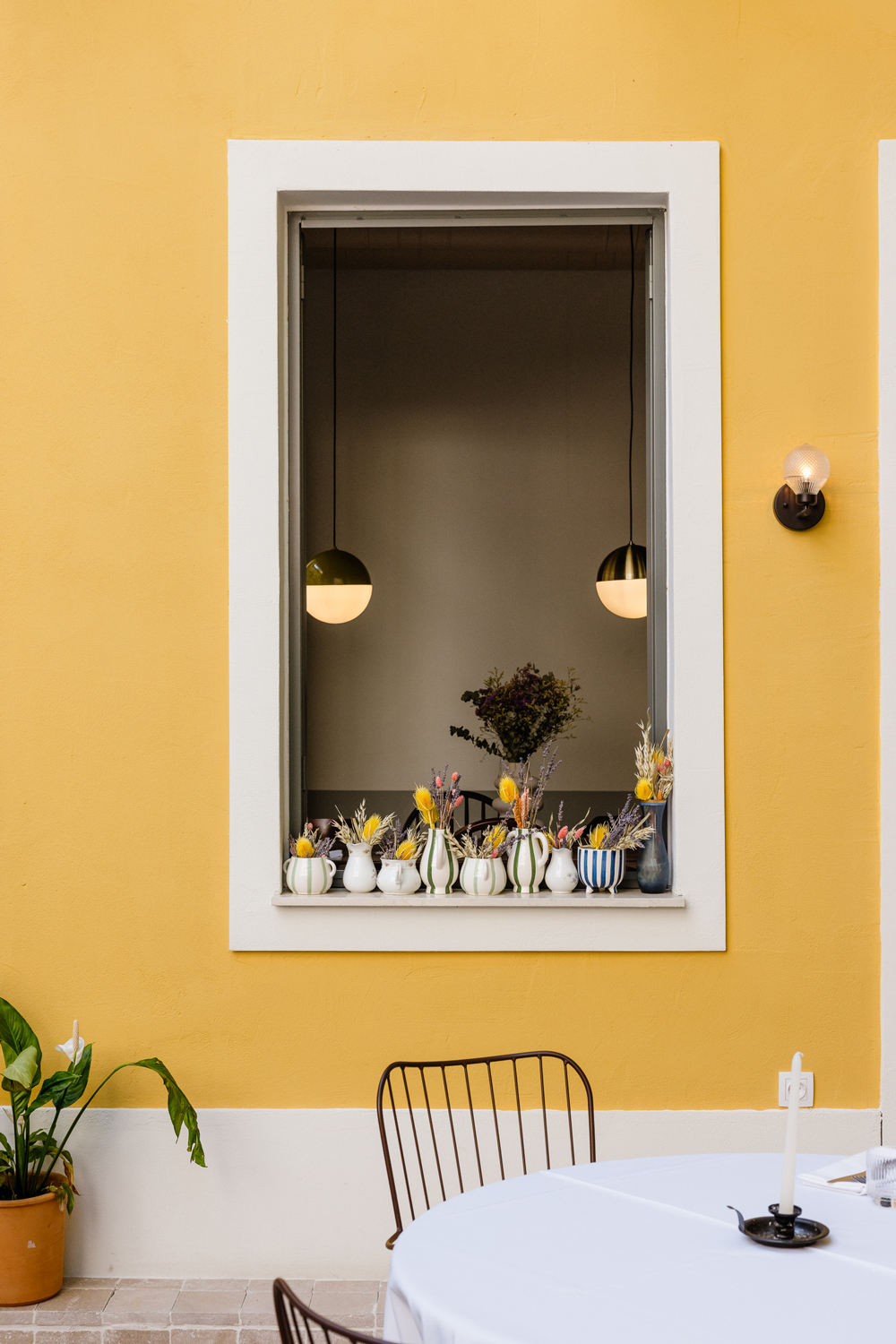 Interior window looking onto the open kitchen, decorated with ceramic tiles of blooming lemon trees.