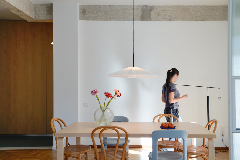 Open-plan living area with restored oak parquet and fluted-glass metal partition.