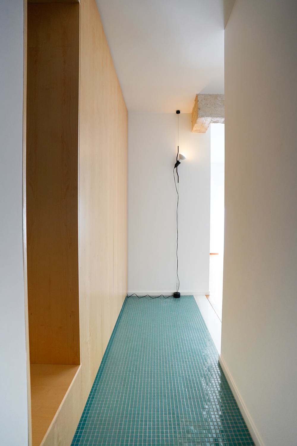 Turquoise tesserae tiles and birch veneer cabinetry in the apartment’s entrance hallway.