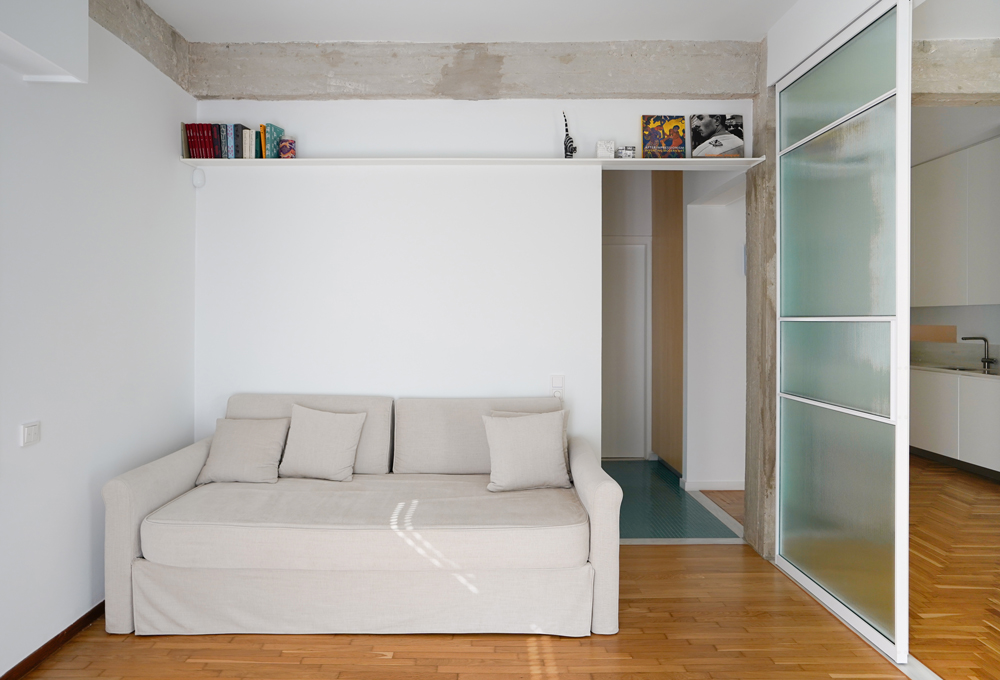 Living room featuring metal shelving, chrome details and warm wooden flooring.