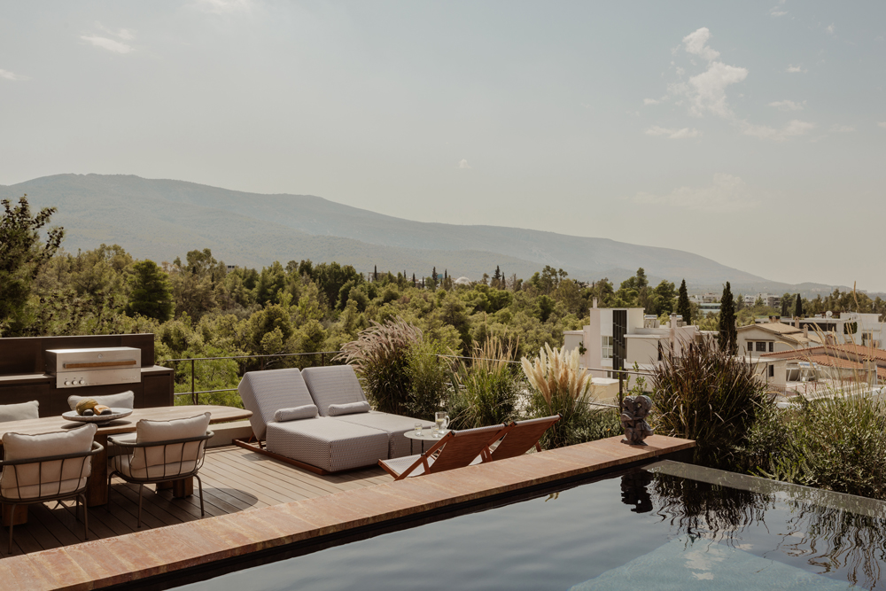 Roof terrace with swimming pool, lush planting and panoramic views over Athens.