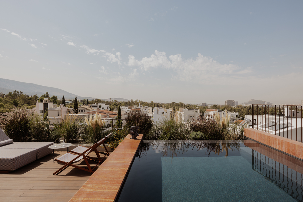 Roof terrace with swimming pool, lush planting and panoramic views over Athens.