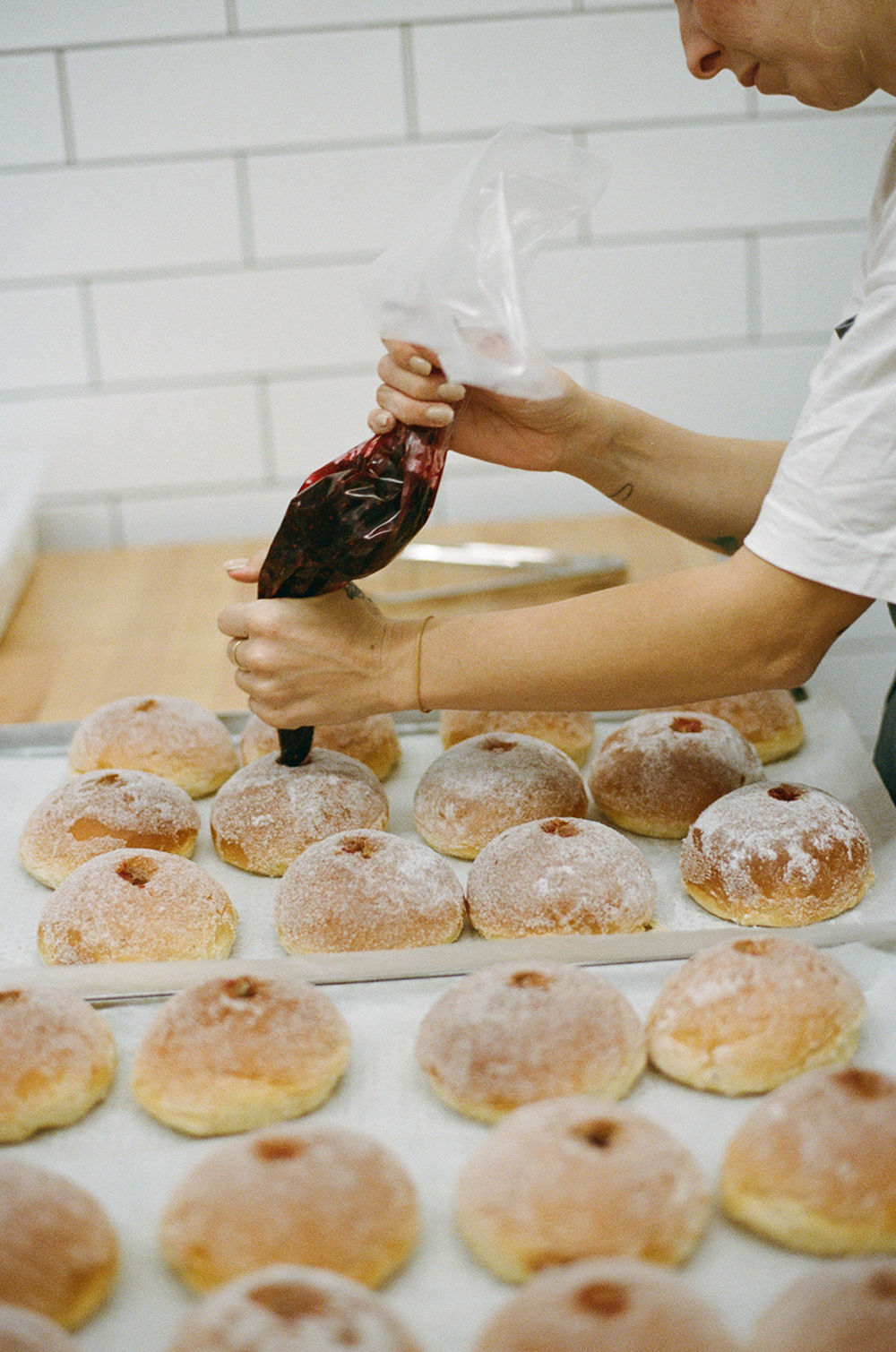 Team member glazing freshly baked cinnamon buns in the Hygge kitchen.