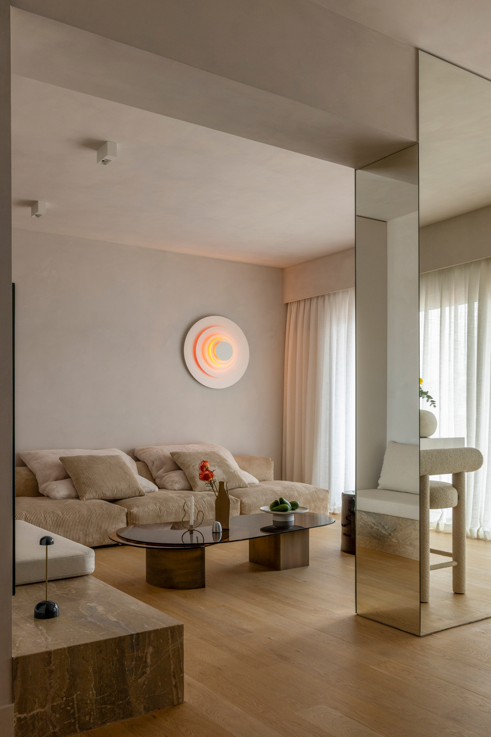 Open-plan living and dining area filled with natural light, featuring mirrored walls and oak flooring.