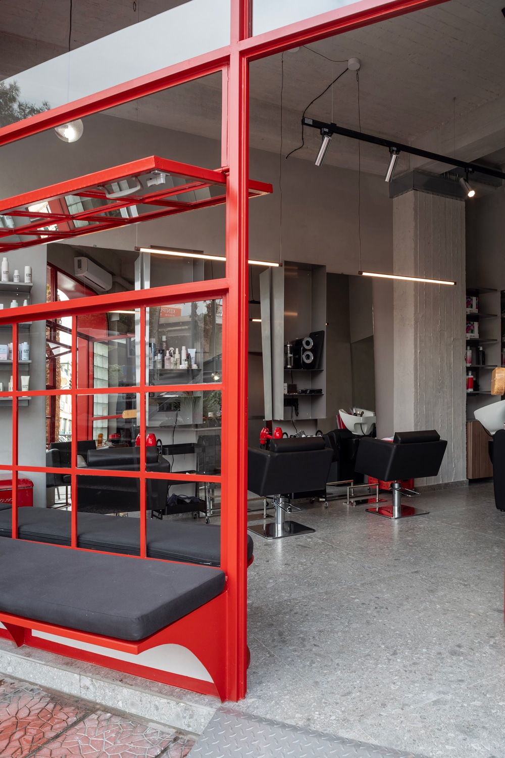 Interior view showing soft grey surfaces, exposed cement ceiling and styling stations.