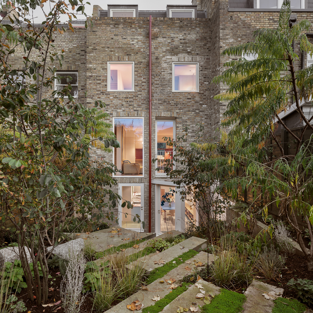Rear façade of the renovated Victorian terrace with large windows overlooking the sculpted, plant-filled garden.