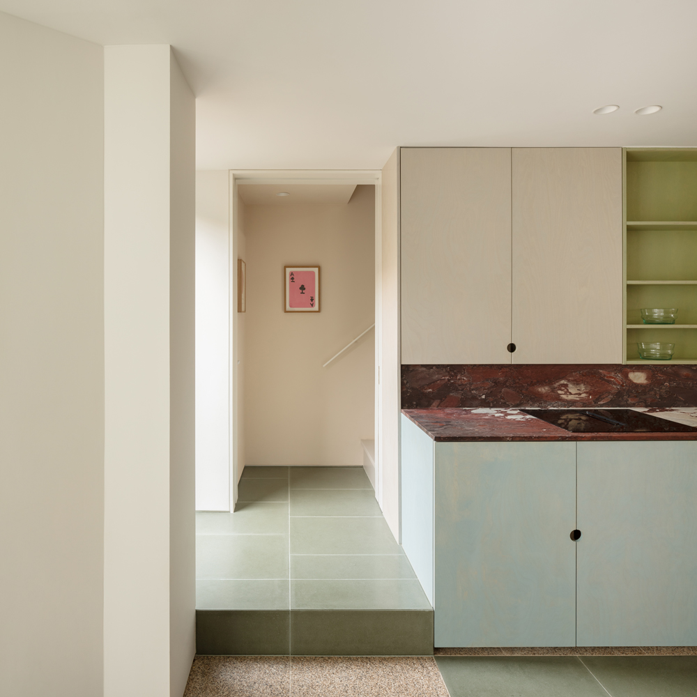 View from the kitchen toward the dining area, showing terrazzo flooring, pale green tiles and a minimalist pendant light.