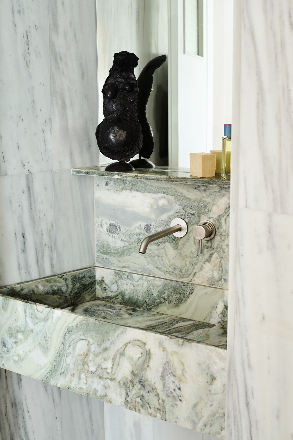 Bathroom lined in white Kavala marble with green Cipollino accents.