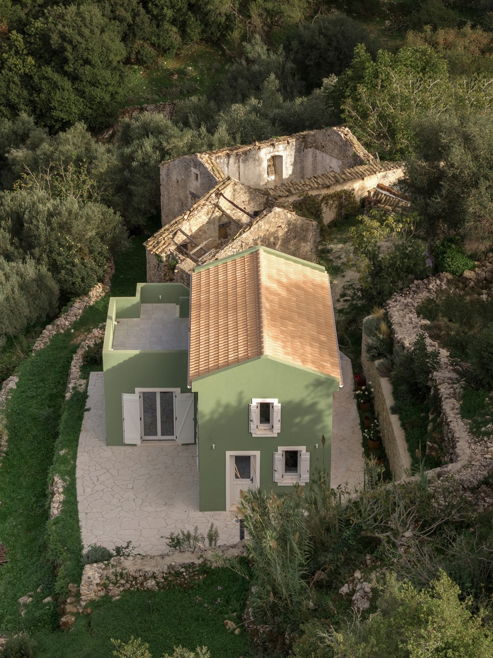 Exterior view of a compact pitched-roof house integrated into the landscape of Vary village, Kefalonia