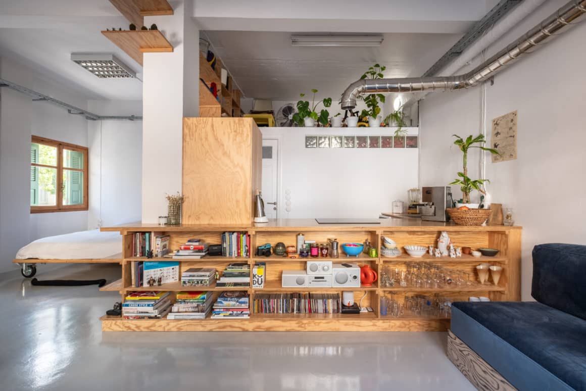 Open-plan studio apartment in Chania with pine plywood partition dividing kitchen and living area