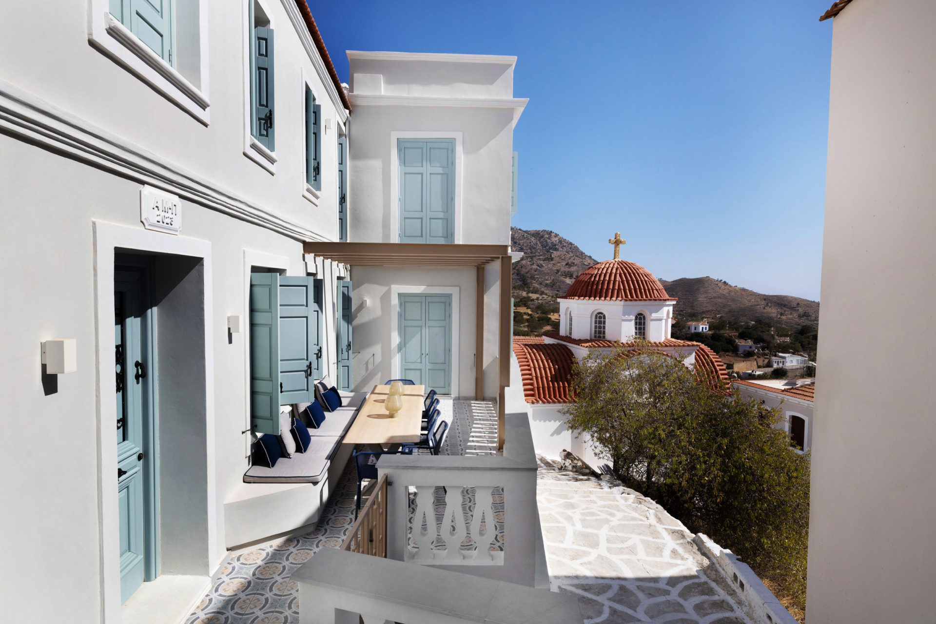 Exterior view of renovated house in Aperi with off-white walls and blue shutters