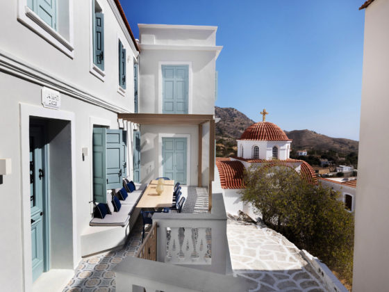 Exterior view of renovated house in Aperi with off-white walls and blue shutters