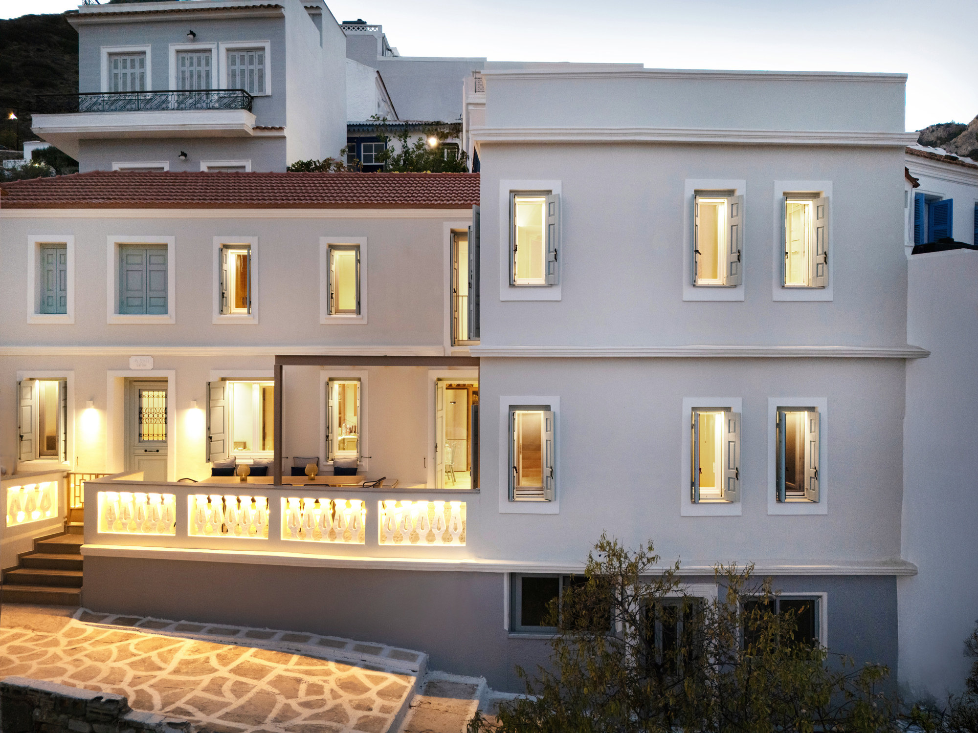 Exterior view of renovated house in Aperi with off-white walls and blue shutters