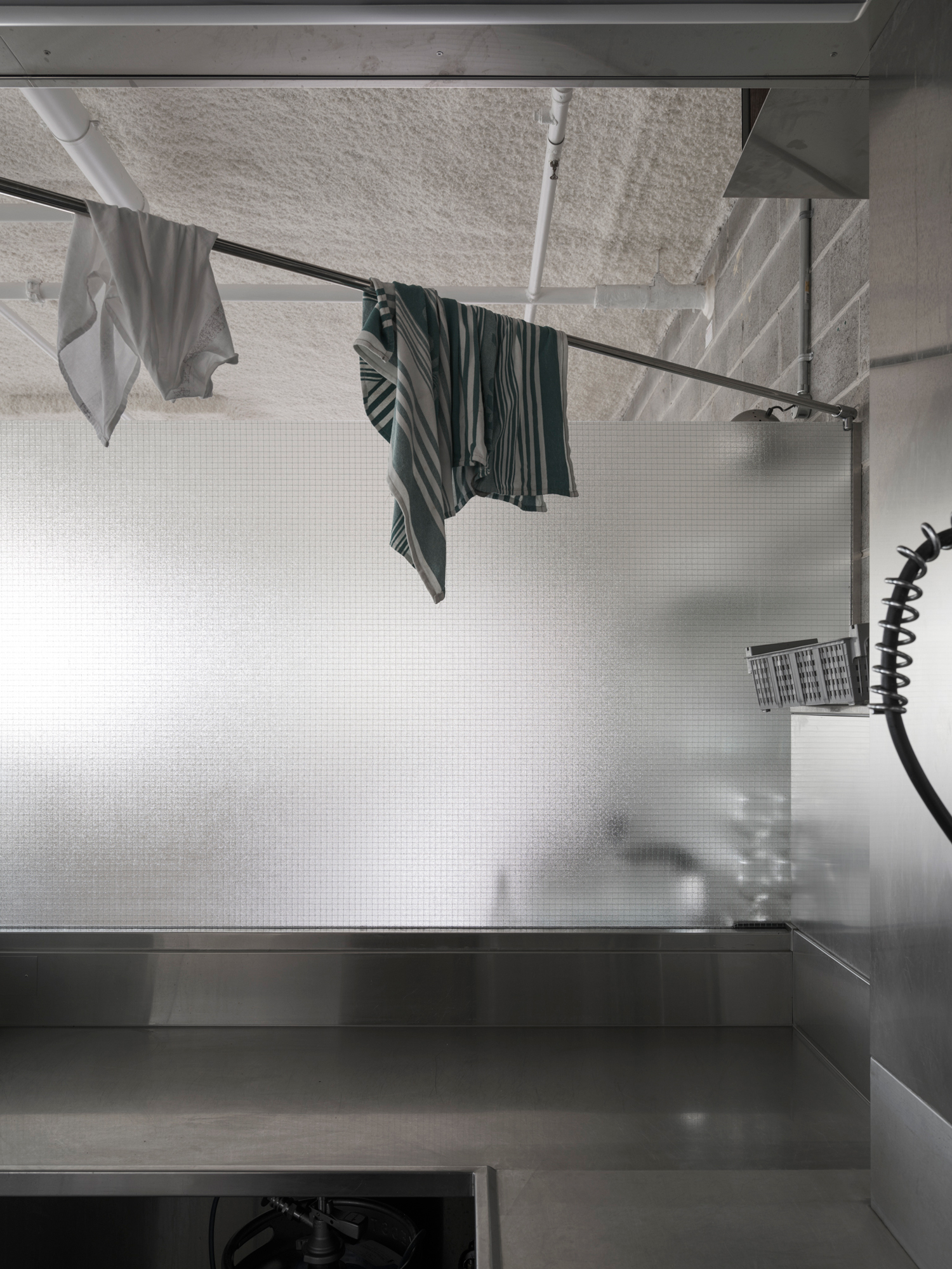 Stainless steel kitchen counter and bar seating at Homer Rogue Taverna by AP Design House