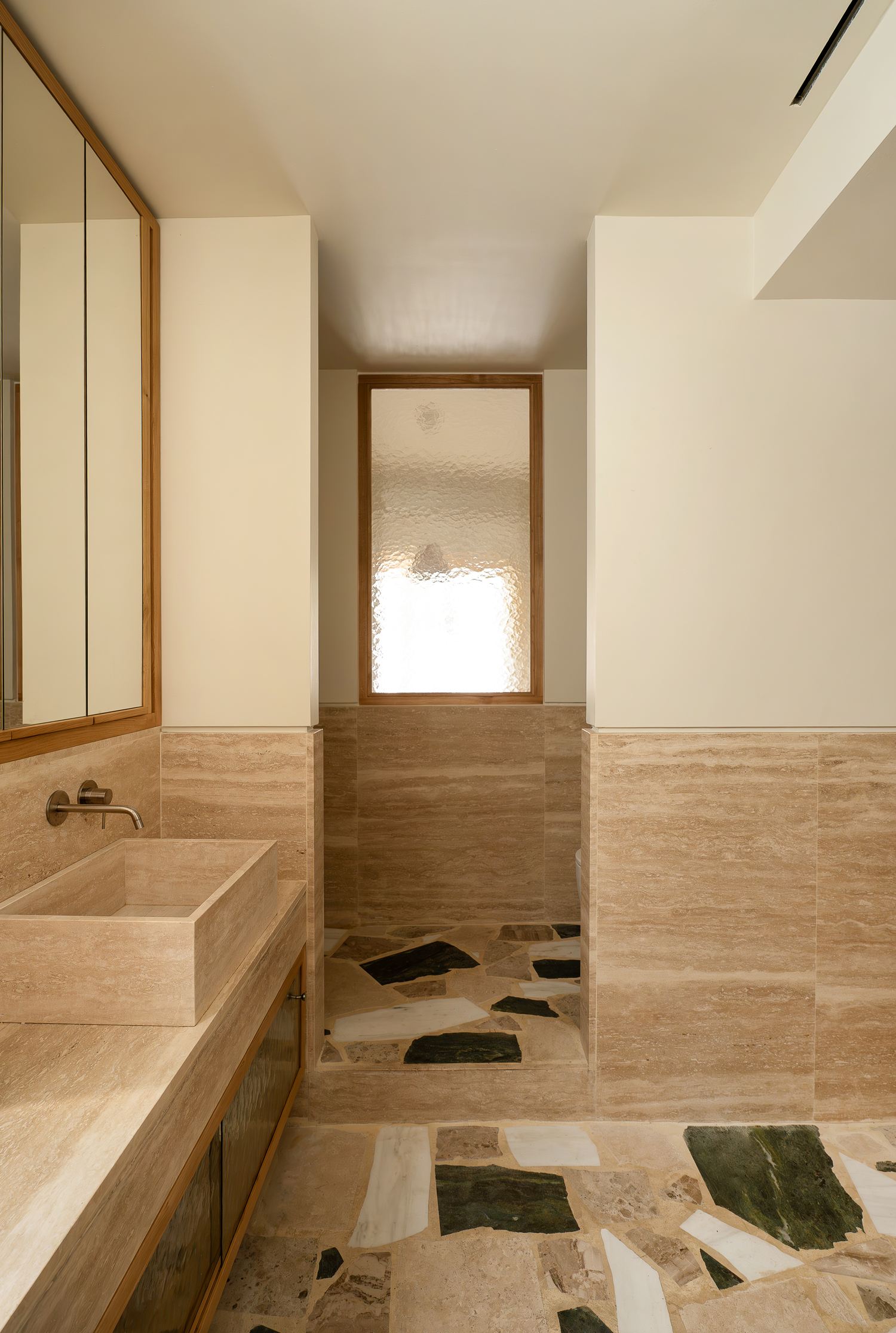 Bathroom with marble surfaces and natural light in renovated Athens apartment