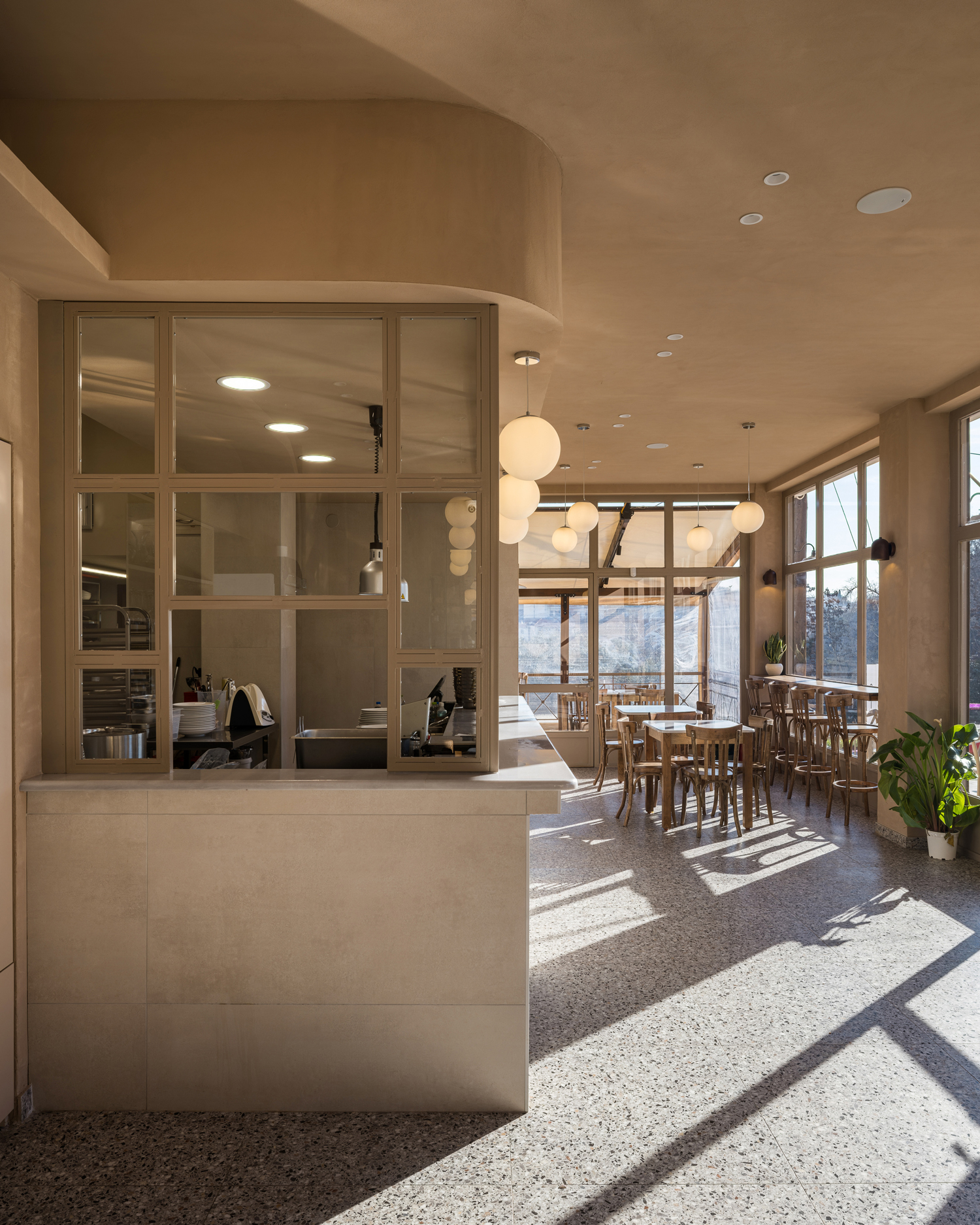 Daylight entering FAI restaurant through large windows casting shadows across terrazzo floor
