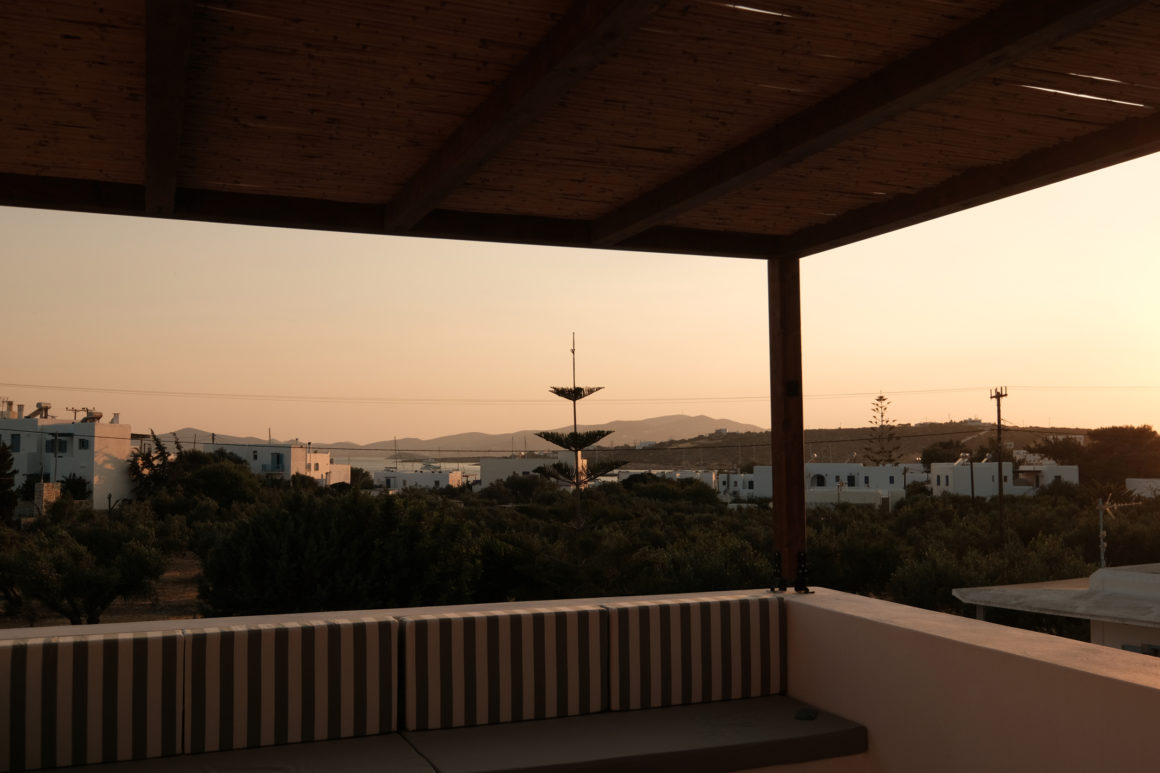Outdoor terrace with wooden pergola casting shadows at Mazi villa in Paros