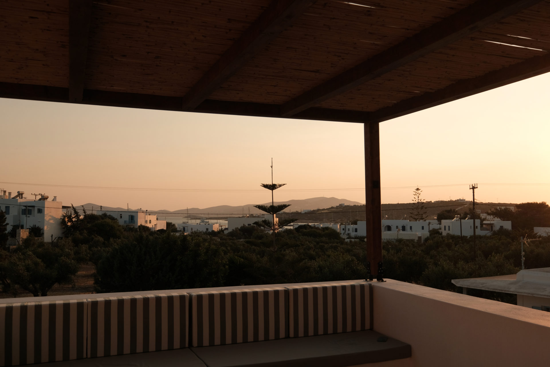 Outdoor terrace with wooden pergola casting shadows at Mazi villa in Paros