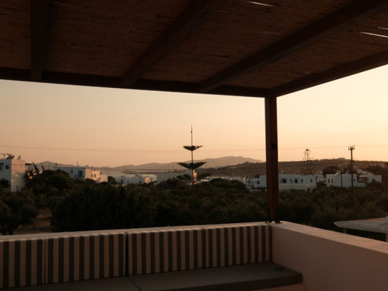 Outdoor terrace with wooden pergola casting shadows at Mazi villa in Paros