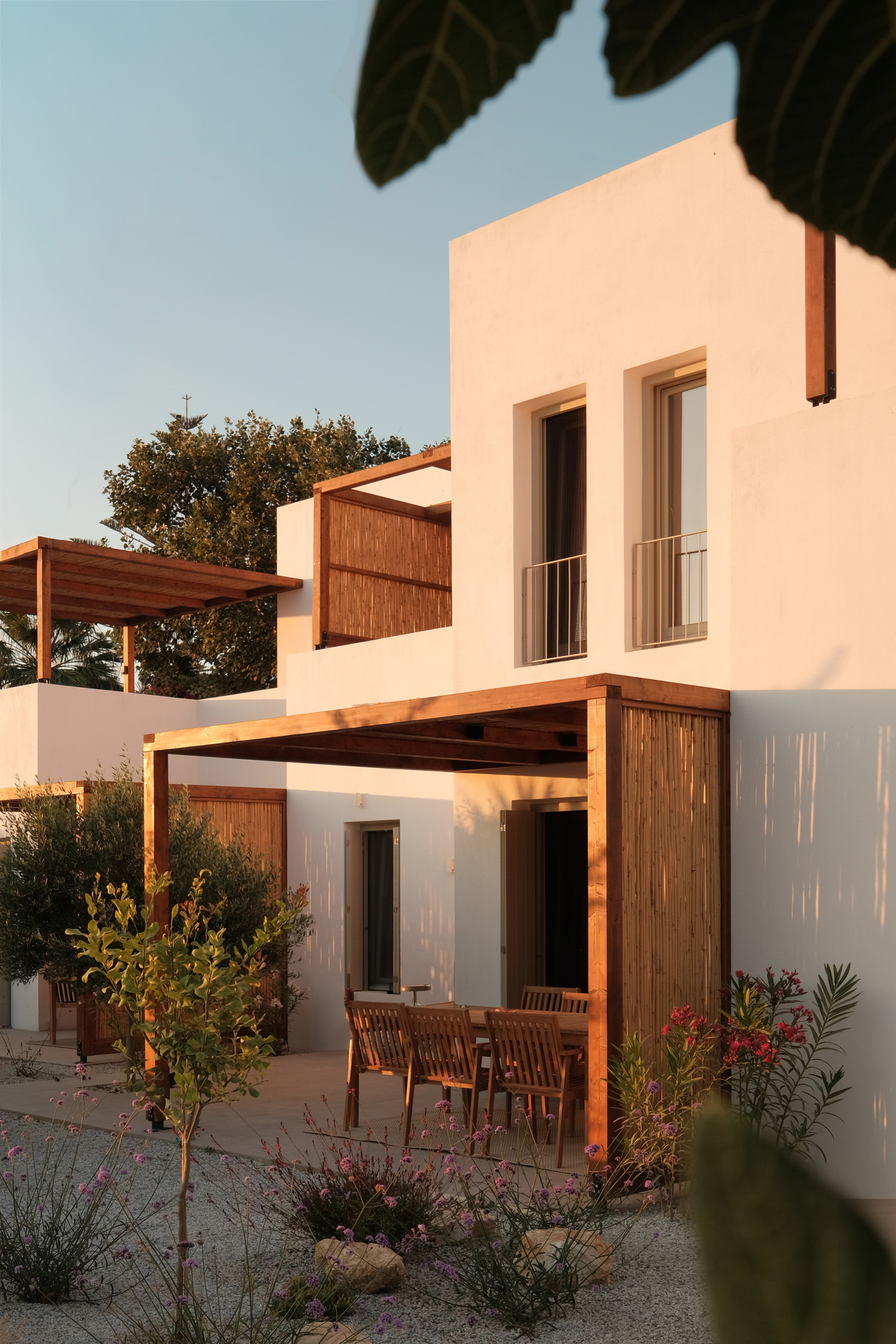 Outdoor terrace with wooden pergola casting shadows at Mazi villa in Paros