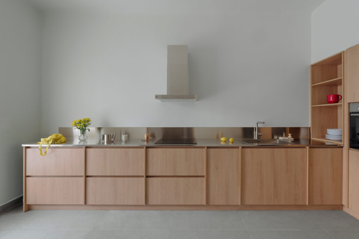 View of the open-plan kitchen and living area with wood cabinetry and stainless steel countertop