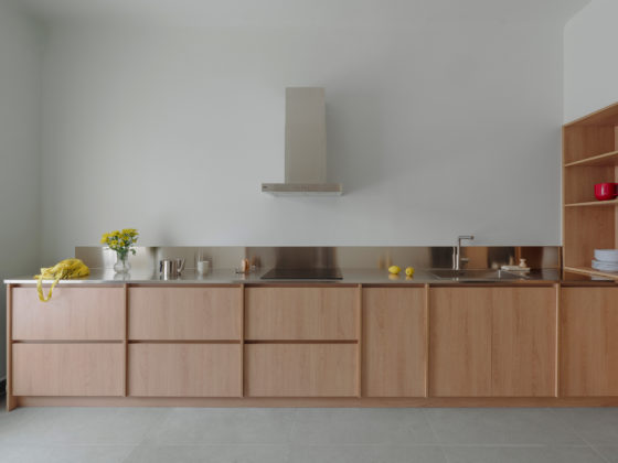 View of the open-plan kitchen and living area with wood cabinetry and stainless steel countertop