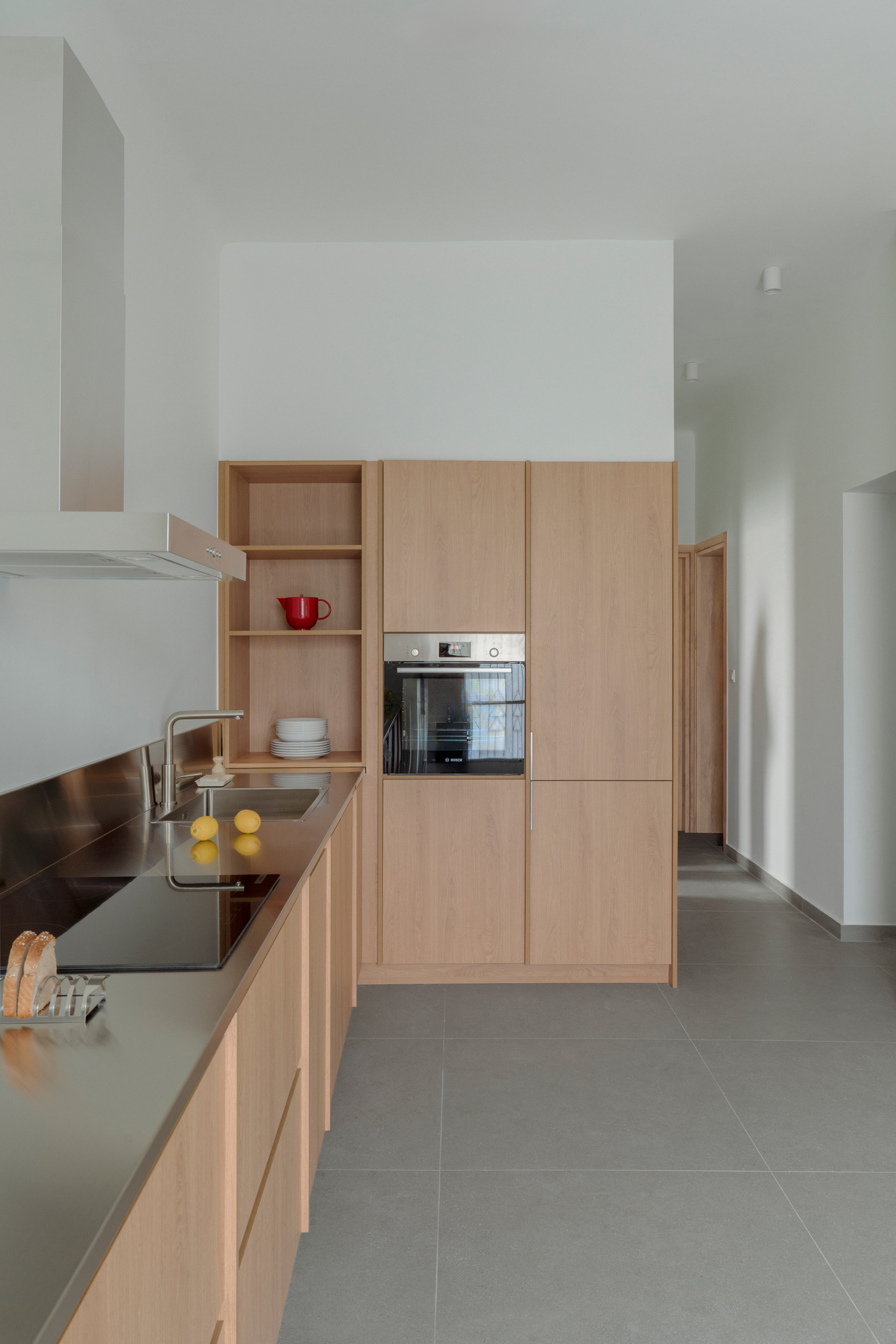 Compact kitchen with stainless steel worktop contrasting with natural materials