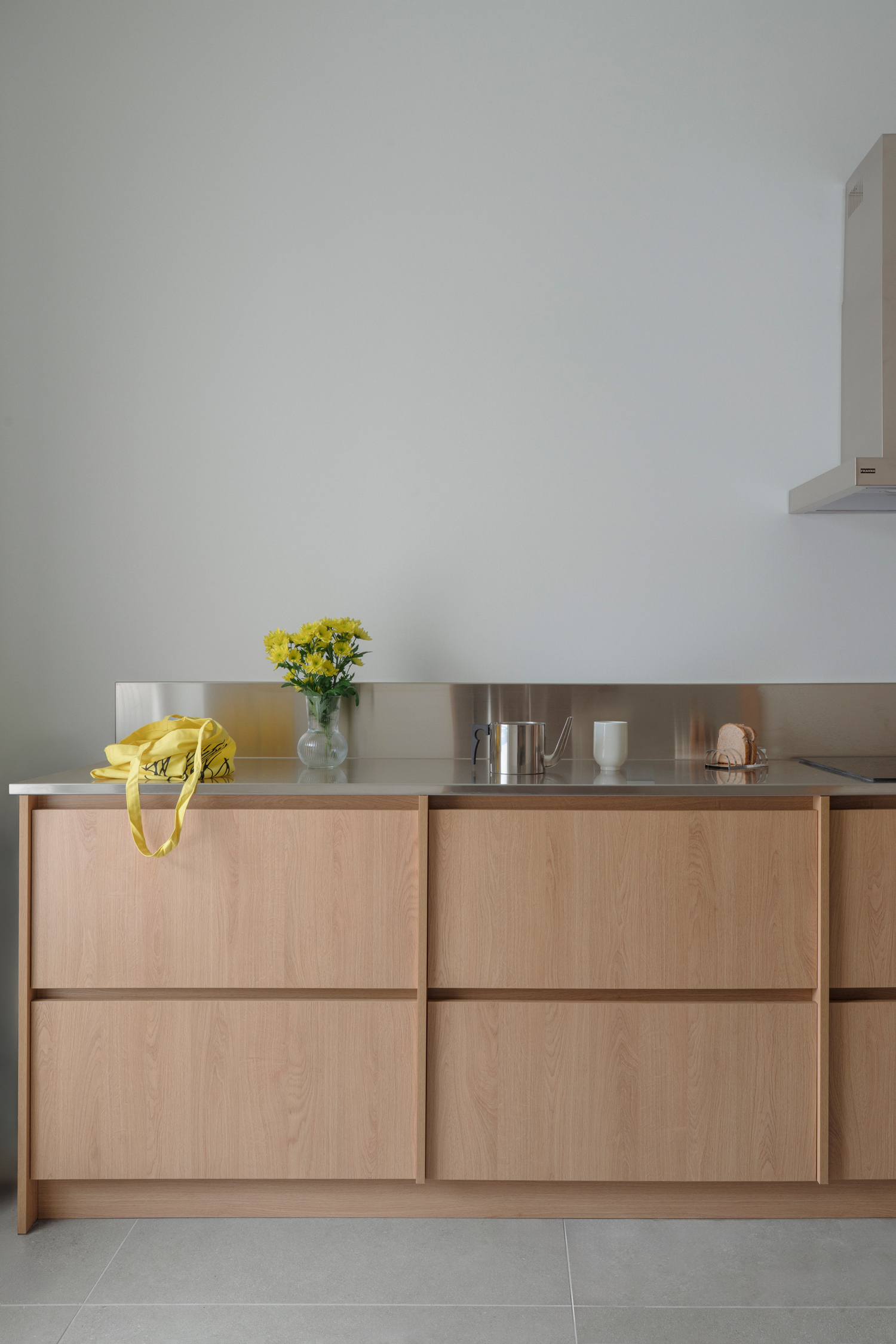Compact kitchen with stainless steel worktop contrasting with natural materials