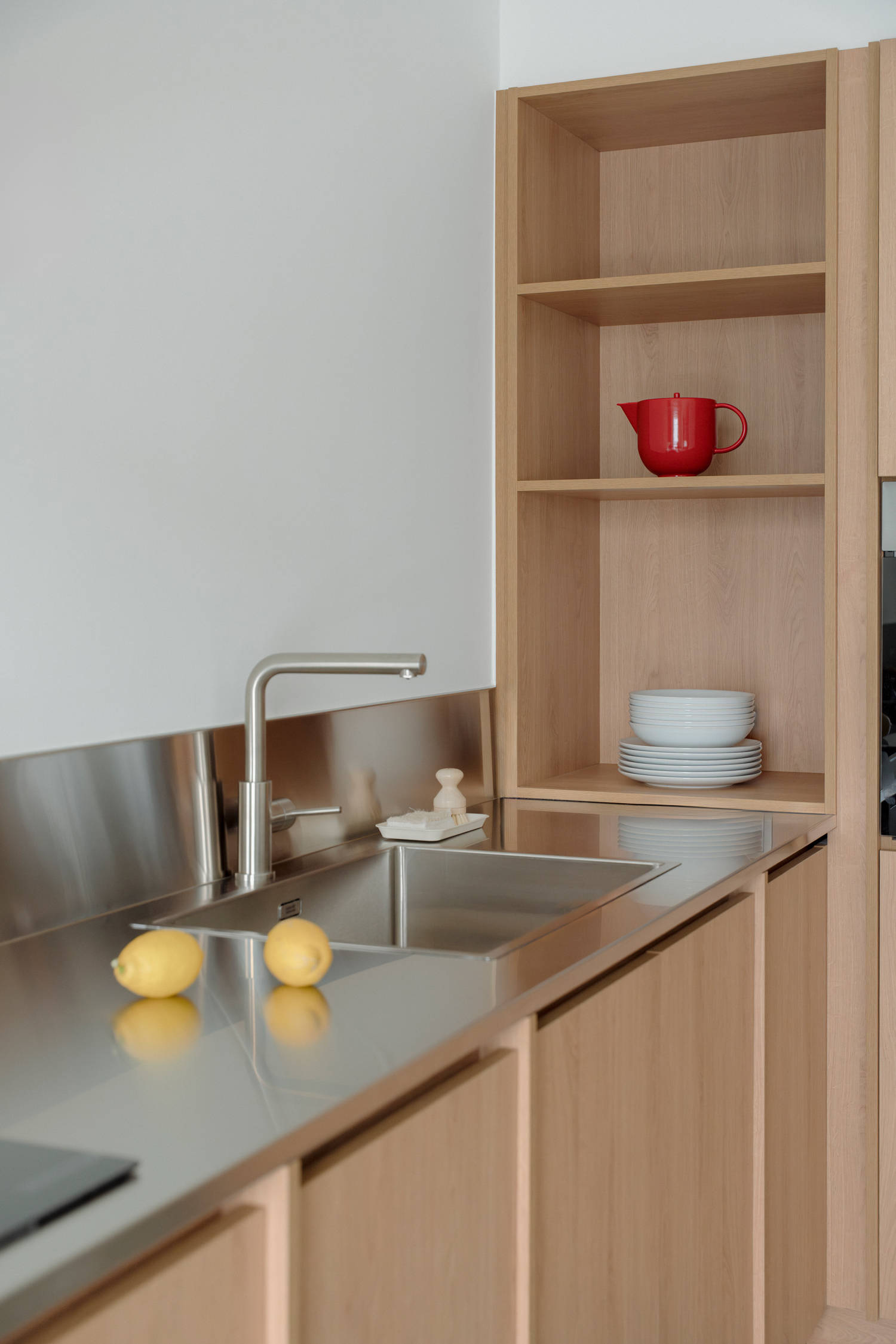 Compact kitchen with stainless steel worktop contrasting with natural materials