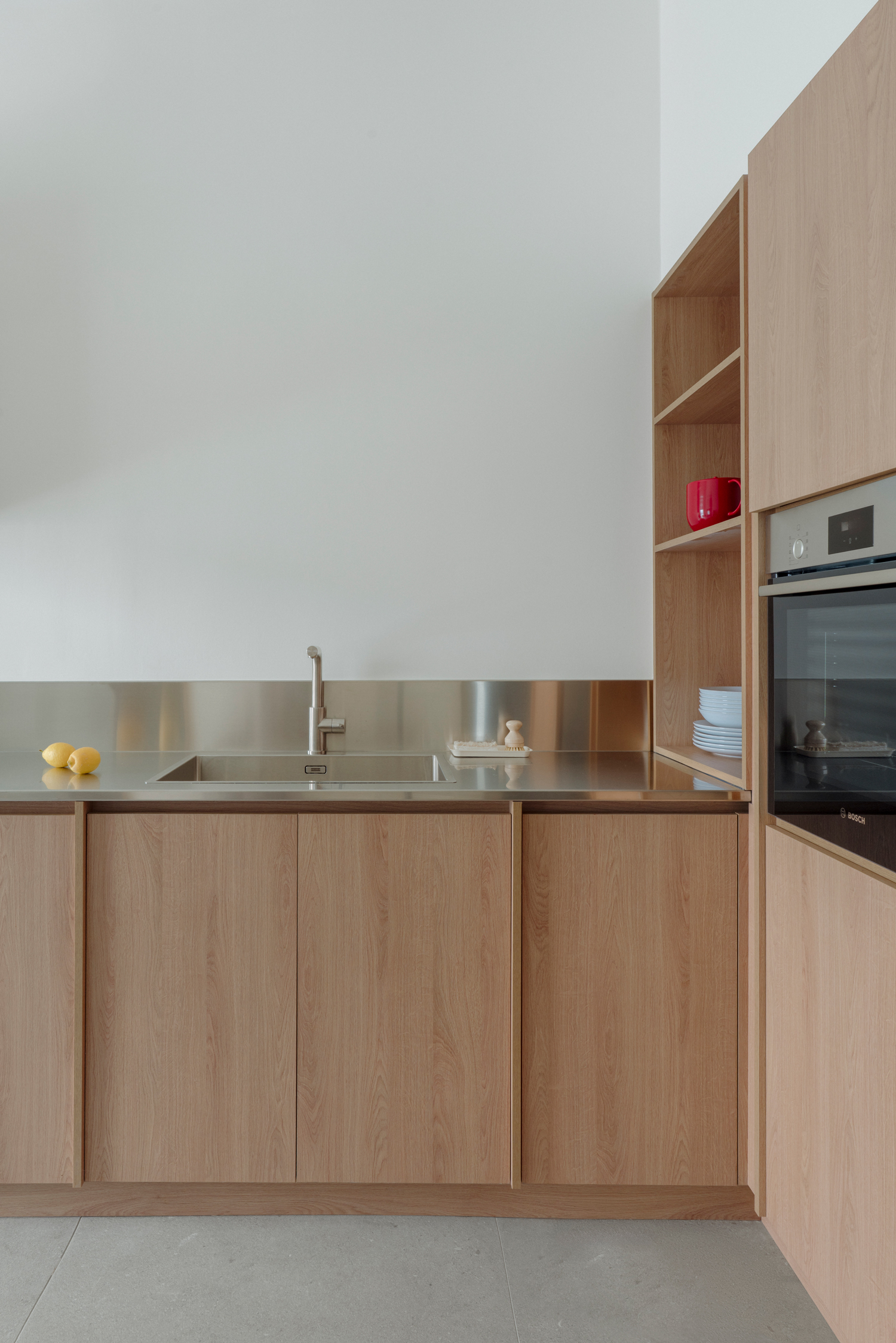 Compact kitchen with stainless steel worktop contrasting with natural materials