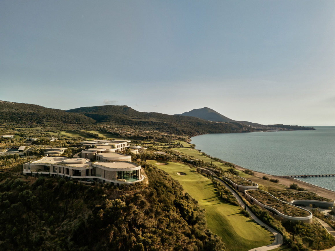 Aerial view of Mandarin Oriental Costa Navarino showing earth-sheltered villas integrated into the hillside overlooking Navarino Bay