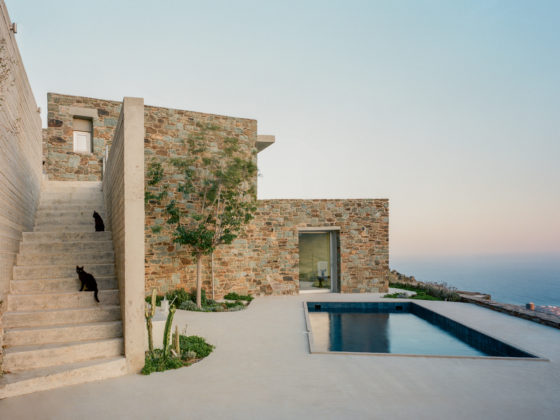 Exterior view of the renovated Tinos house with stone walls, whitewashed volumes and swimming pool overlooking the landscape.