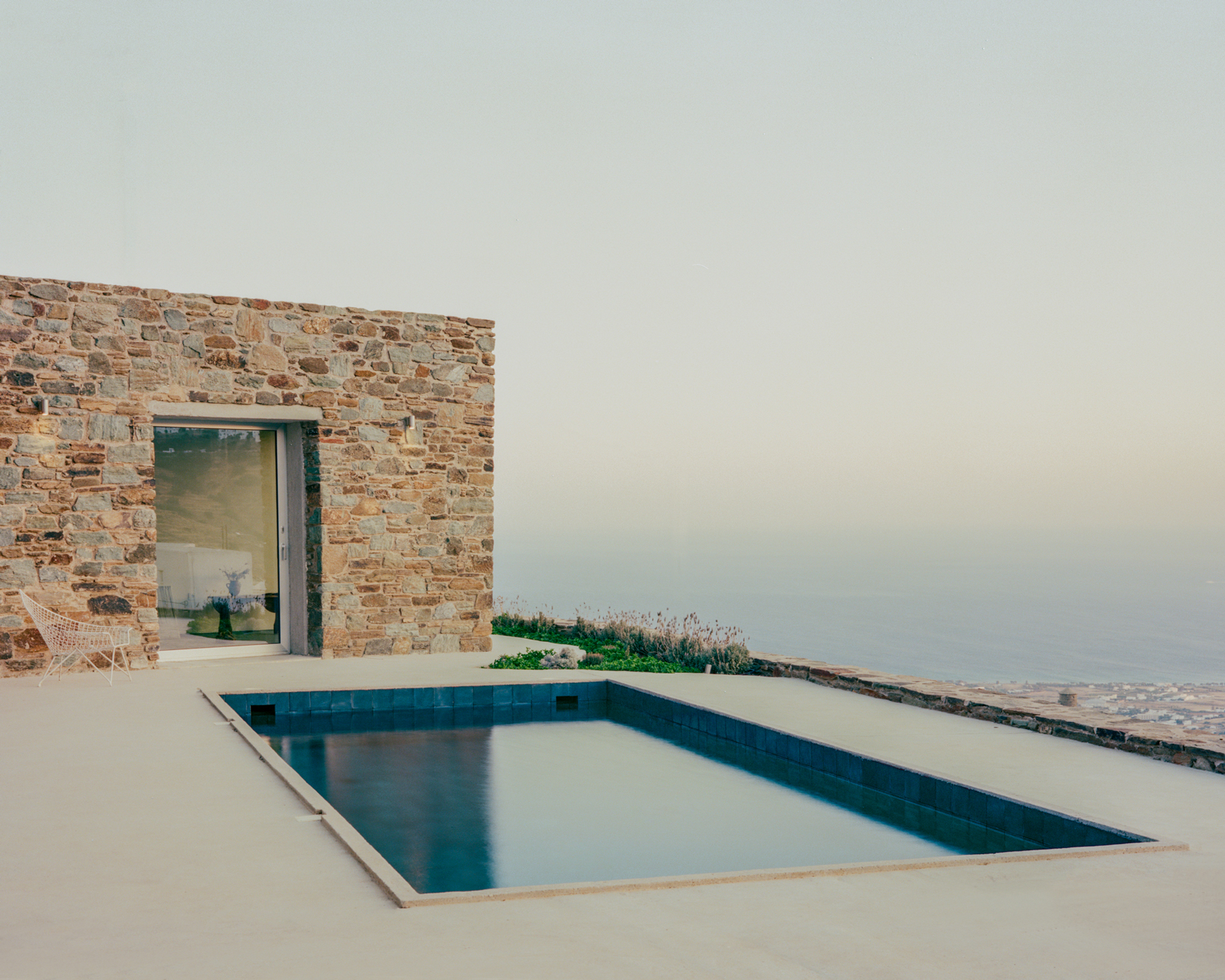 Swimming pool and outdoor living area beside the house overlooking the Cycladic landscape.