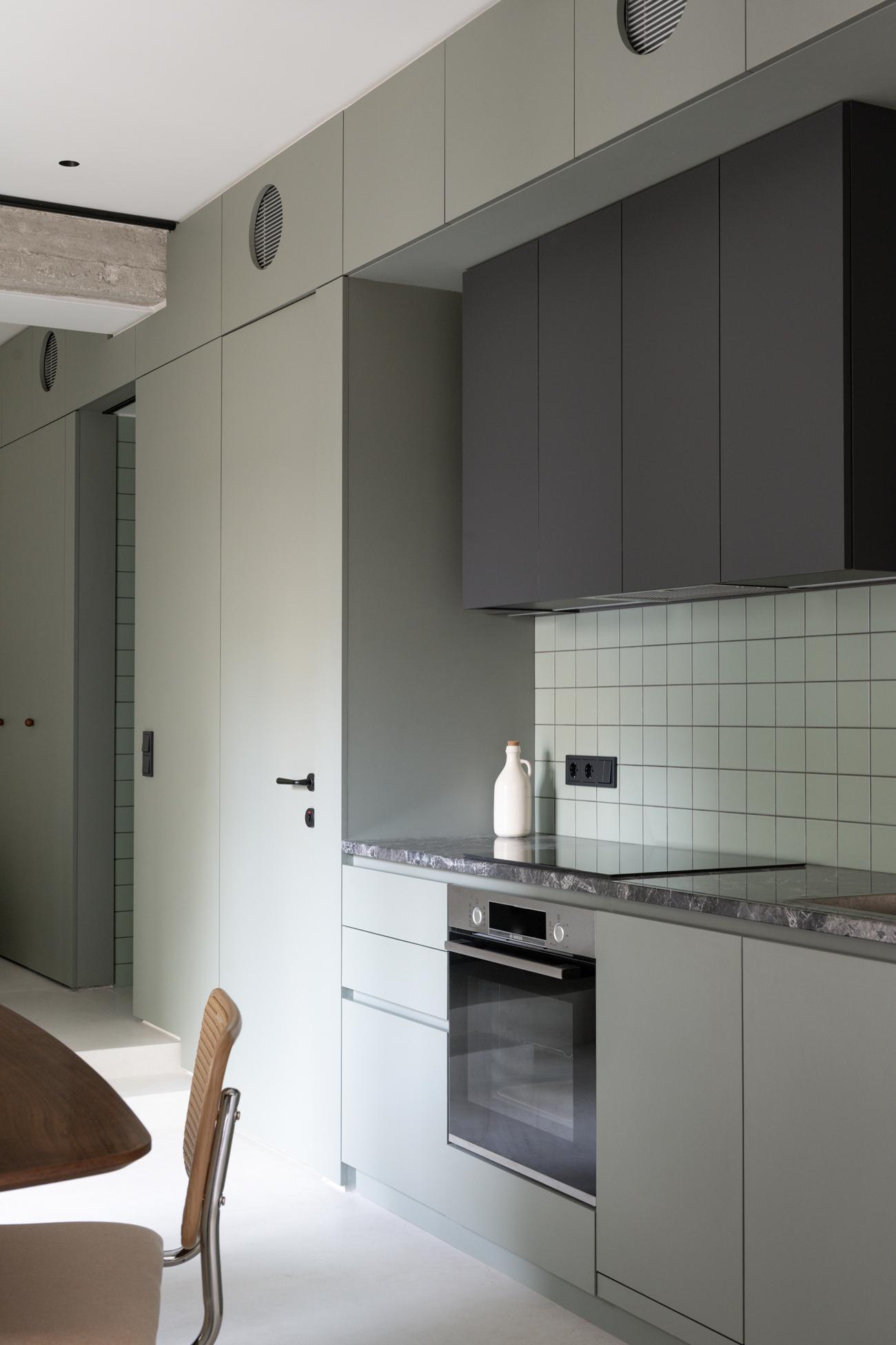 Close-up of the green cabinetry and stainless-steel kitchen detailing.