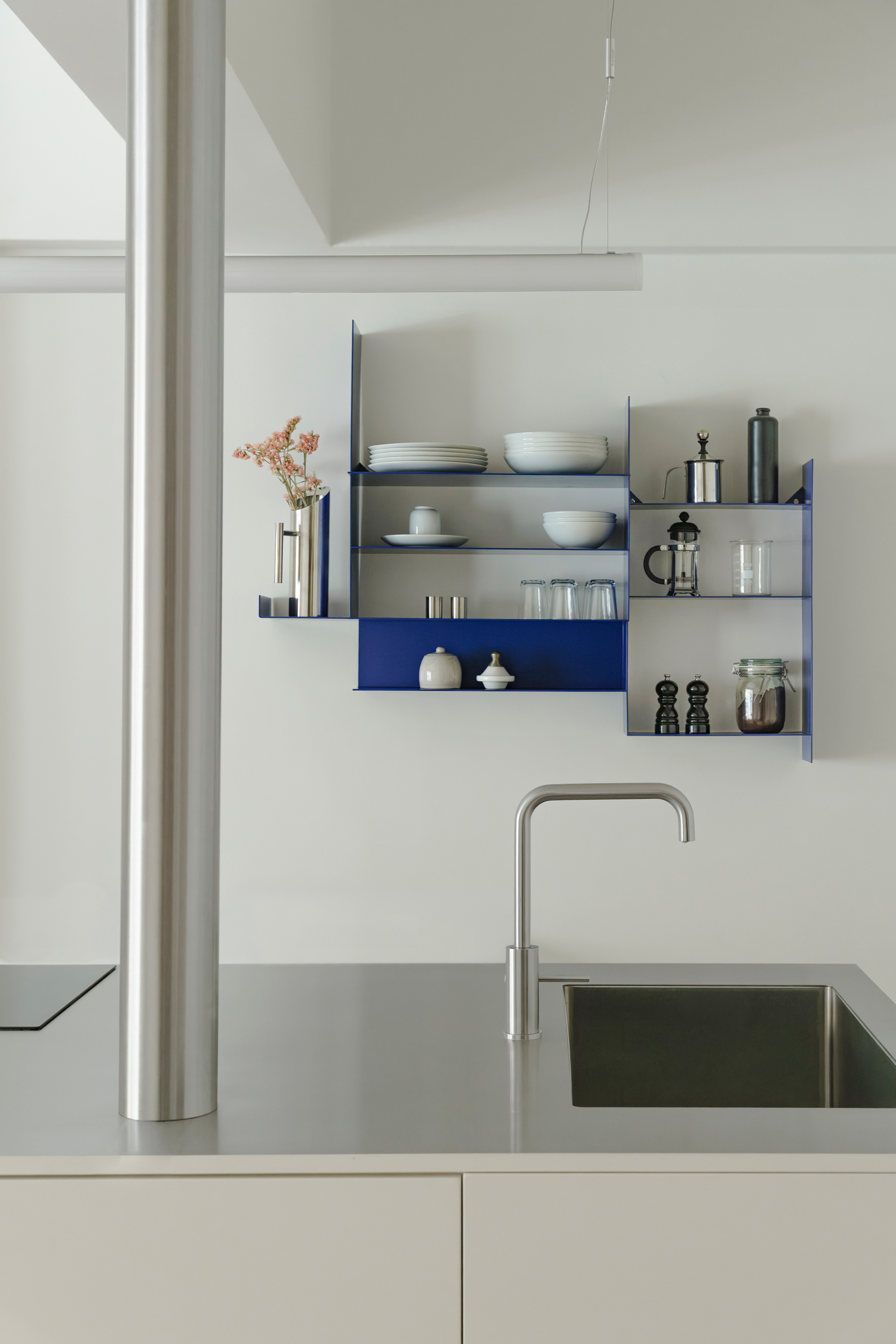 Open kitchen and dining area with stainless-steel finishes, timber flooring and minimalist detailing.