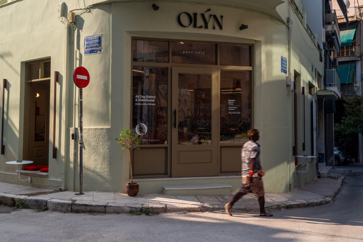 Exterior view of OLYN, a contemporary gluten-free bakery by Karn Studio, with fully opening façades on a corner site in Athens' Acropolis district.